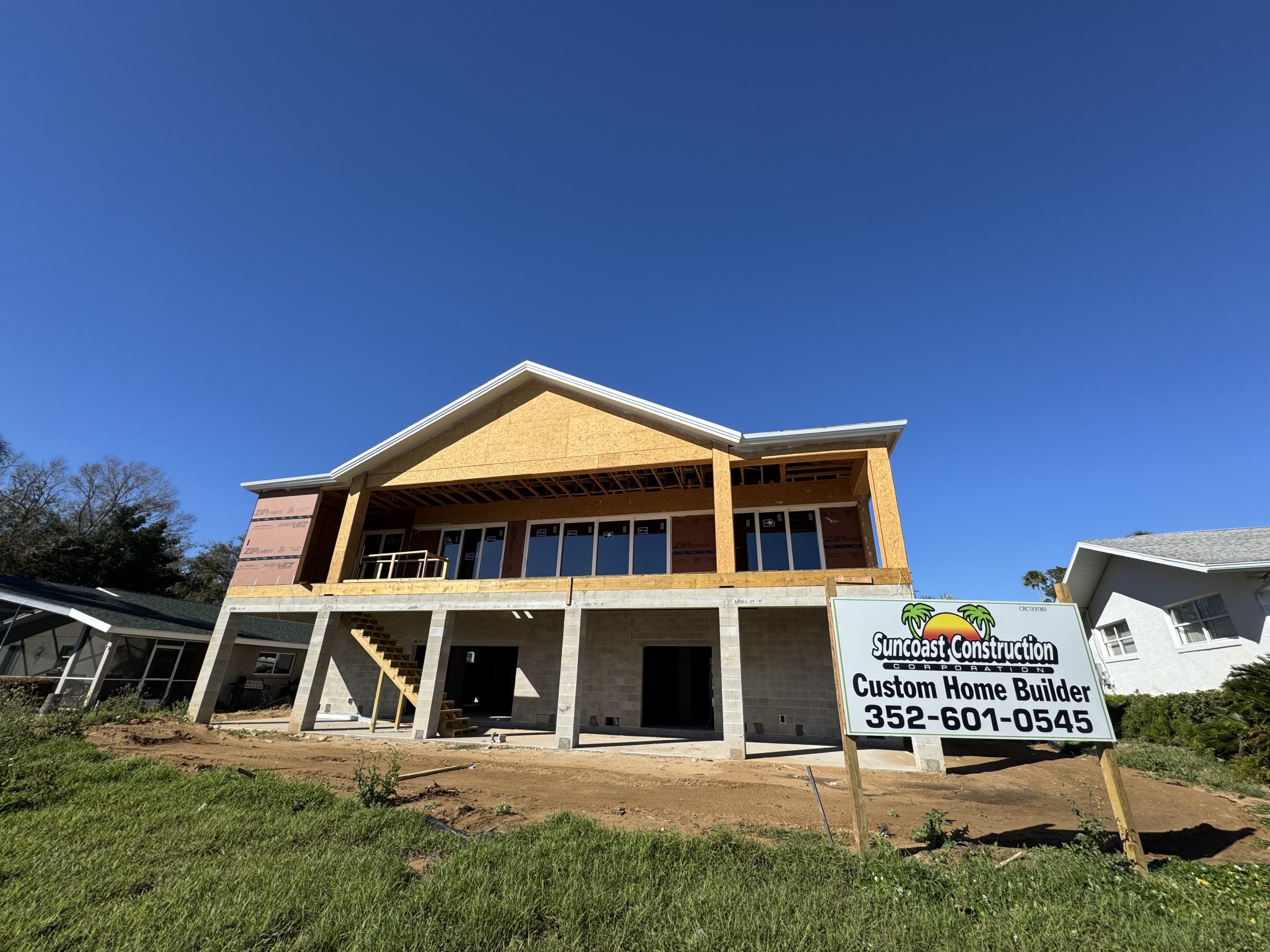 home windows Two-story home under construction with multiple window openings for window installation and a custom home builder sign in front.