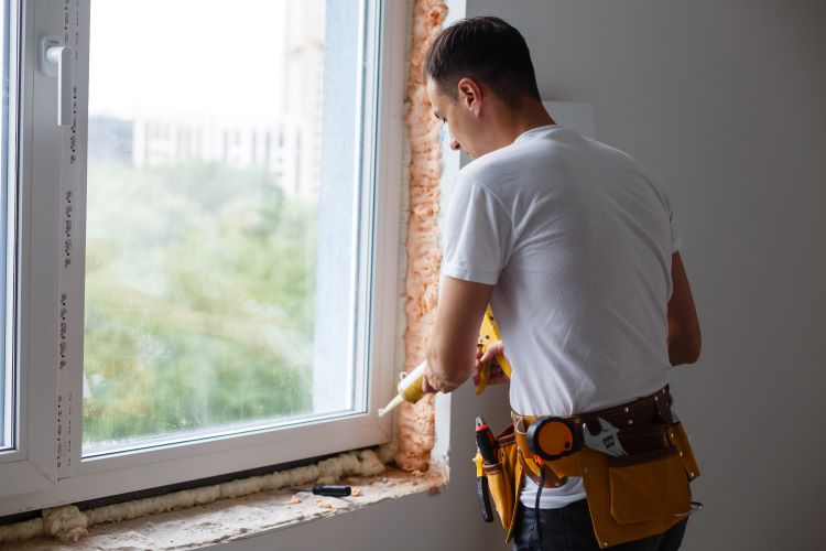 Window Frame Repair and Resealing Service Technician sealing and caulking a window during window frame repair.