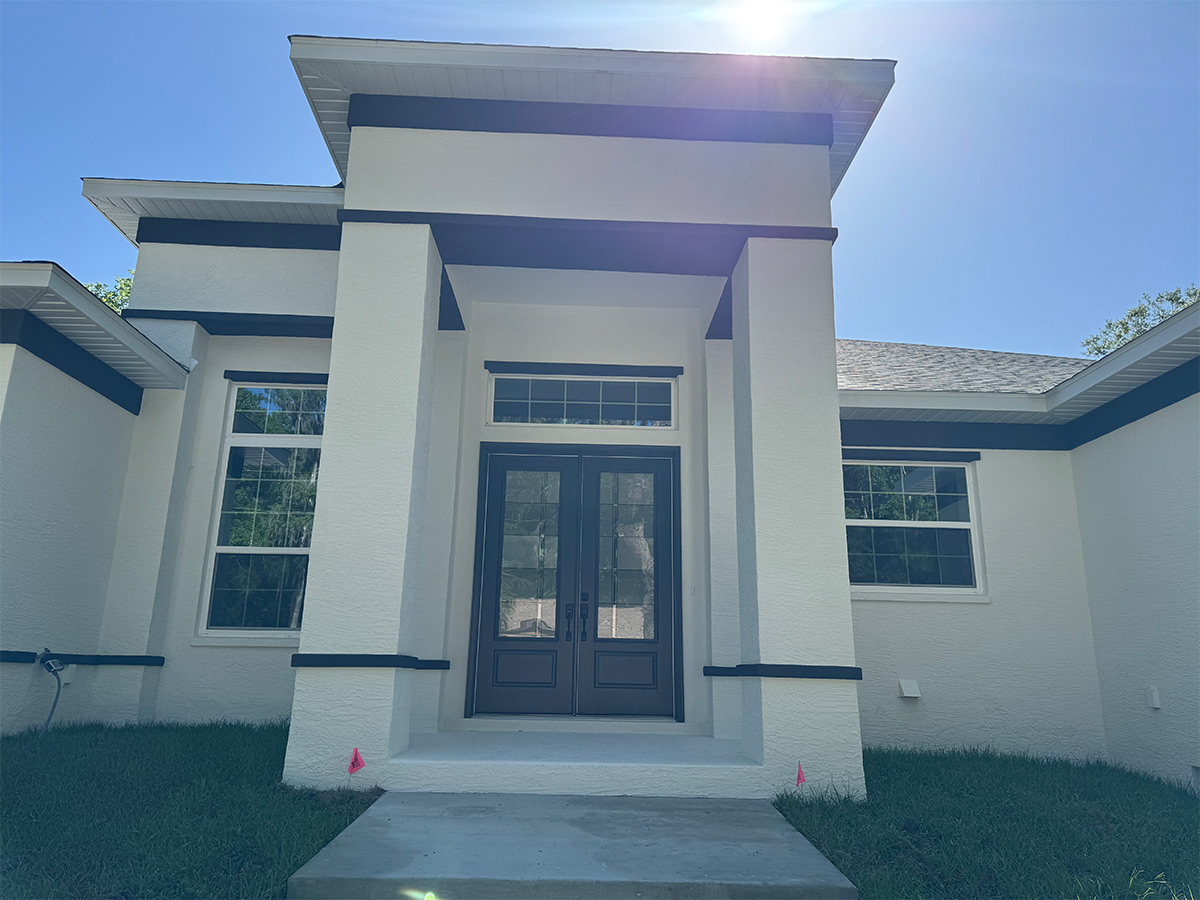 Black Exterior Double Front Doors With Transom Window Black exterior double front doors with glass panels and a transom window installed on a Florida home by Tropical Window.