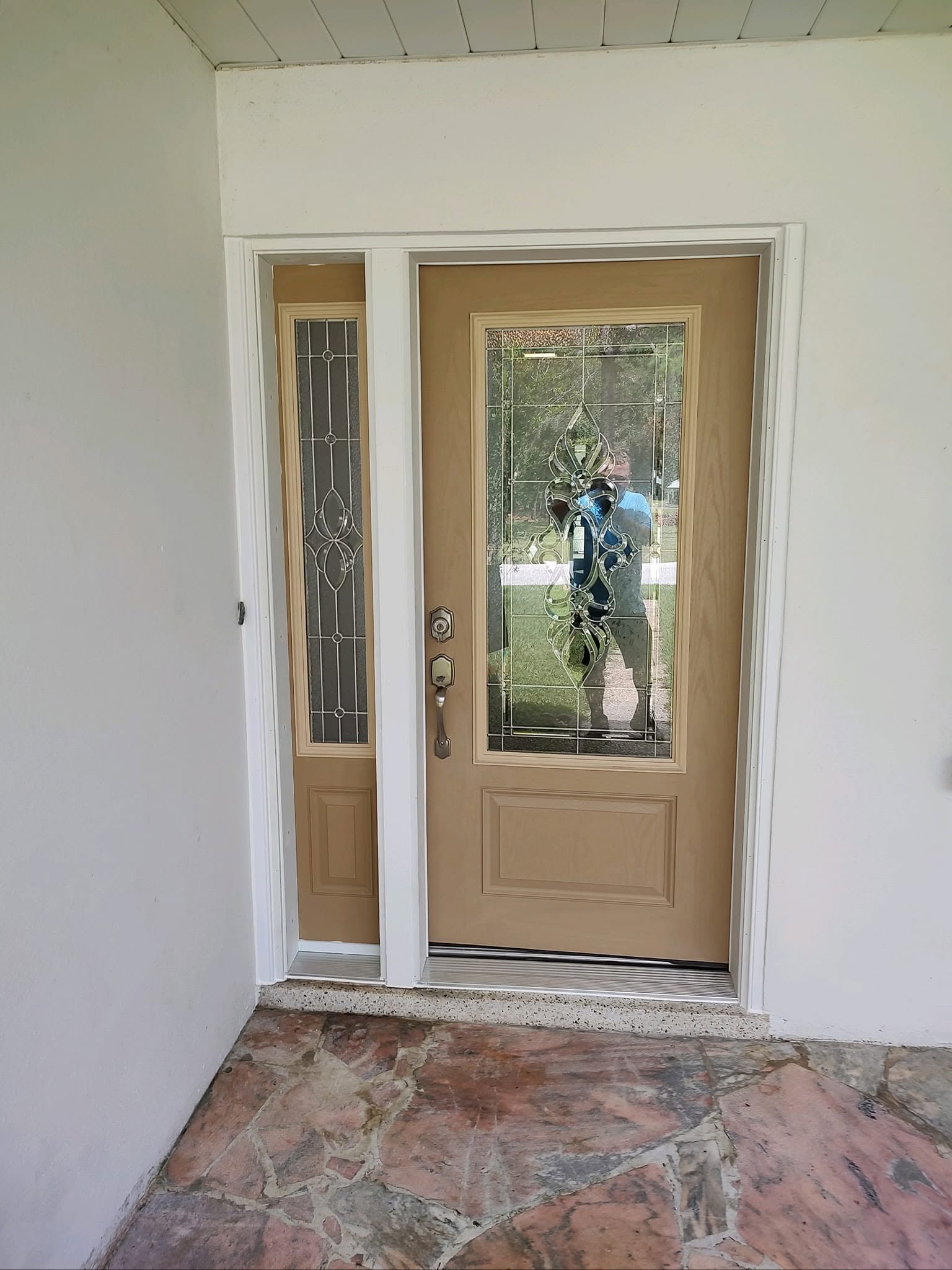 Fiberglass Front Door With Decorative Glass and Sideline Tan fiberglass front entry door with decorative glass and matching sidelite installed on a covered entryway.
